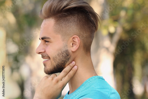 Young man checking pulse outdoors on sunny day