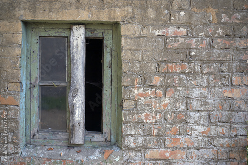 A broken window in an old abandoned brick building.