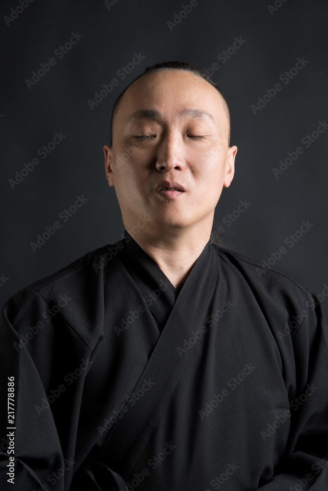 Portrait of a man asian samurai with closed eyes on a black background Portrait of a man asian samurai with closed eyes on a black background
