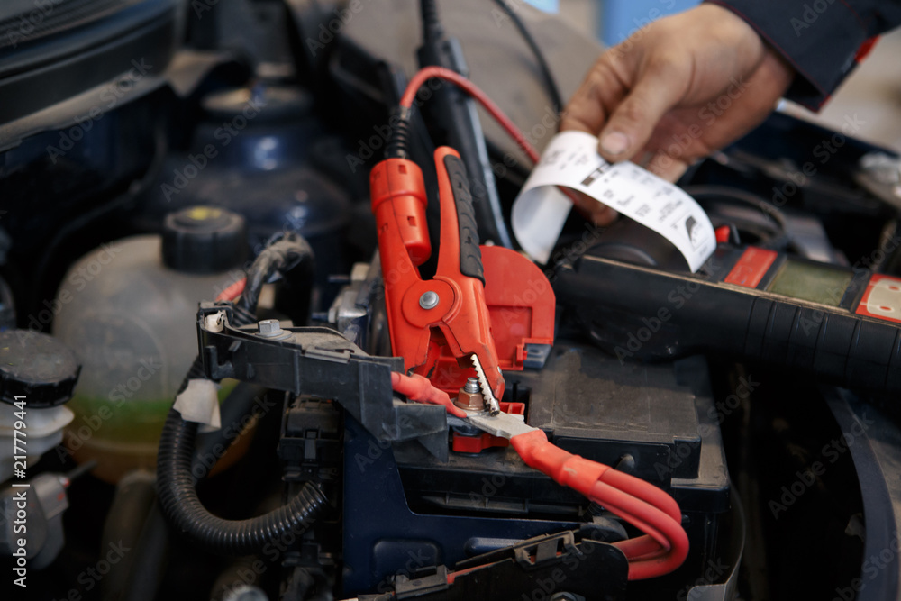 Obraz premium Mechanic using booster cables to start-up a car engine