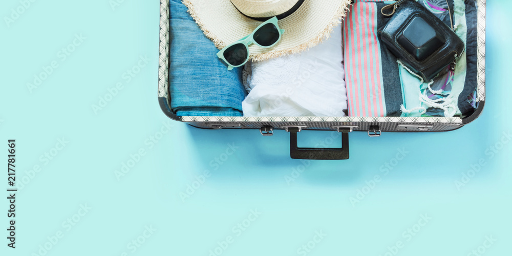 Open suitcase with female clothes for trip on pastel blue. Top view with copy space. Summer concept travel. - obrazy, fototapety, plakaty 