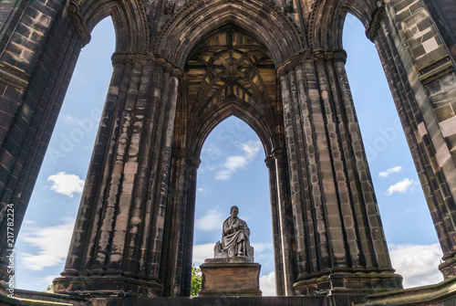 Edinburgh, Scotland, UK - June 13, 2012: Looking through Scott Monument with blue sky in back. Statue of Sir Walter Scott in center framed by dark stone pillars.