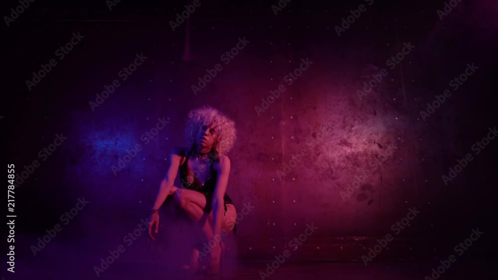 Attractive young woman with curly blond hair wearing lingerie dancing in a dark room with steam. Locked down real time medium shot Attractive young woman with curly blond hair wearing lingerie dancing in a dark room with steam. Locked down real time medium shot