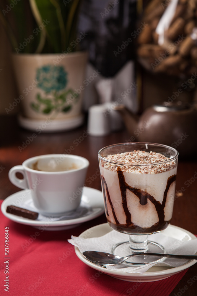 Tiramisu with a cup of coffee in a restaurant on a red tablecloth Tiramisu with a cup of coffee in a restaurant on a red tablecloth