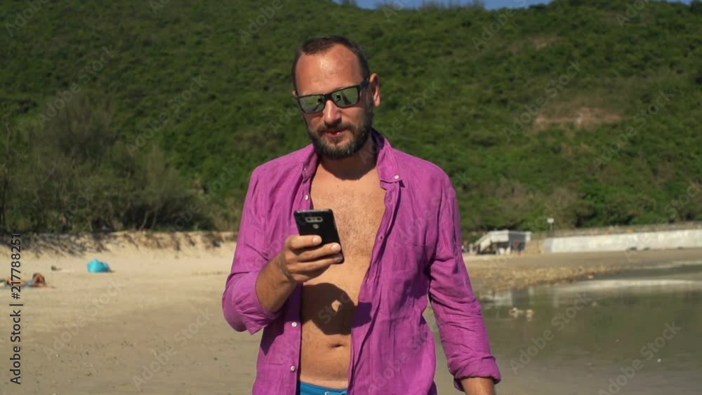 Young, happy man texting on smartphone, walking on beach, super slow motion
Young, happy man texting on smartphone, walking on beach, super slow motion