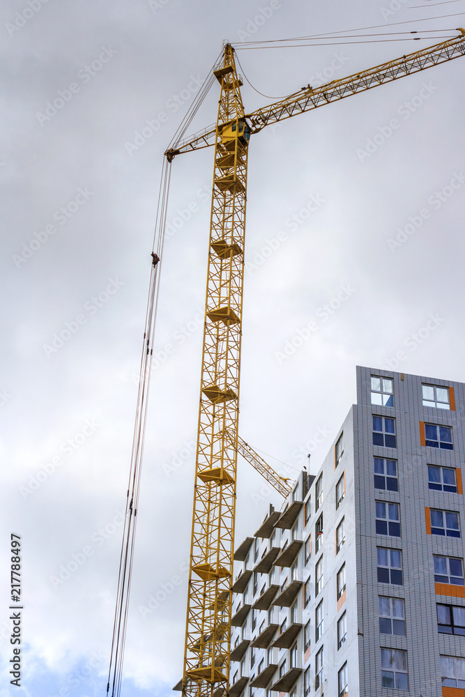 Cranes and building construction and the clouds. Vertical composition