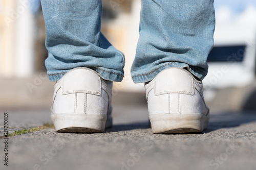 Flat foot, sole, posture concept. Irregular wear heel male shoes, closeup back view outdoors, blurred background. Flat feet and fast wear of shoes