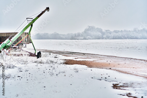 An old grain auger in a snowy field on an overcast day. photo