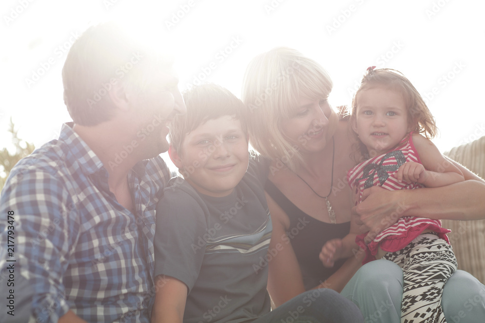 family with two children sitting together and looking at camera family with two children sitting together and looking at camera