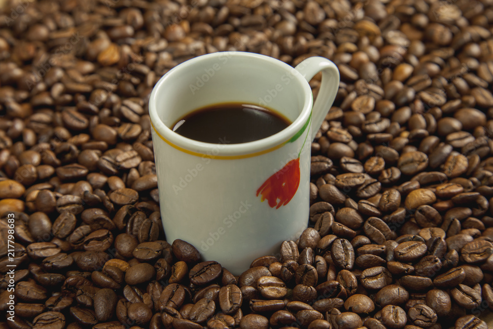 Fototapeta premium Taza de café rodeada de café tostado