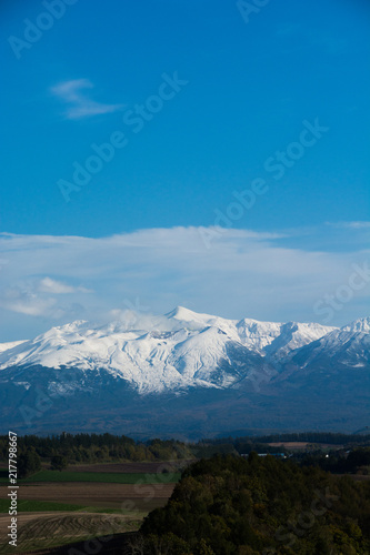 秋の大地と冠雪した高い山　十勝岳 © kinpouge