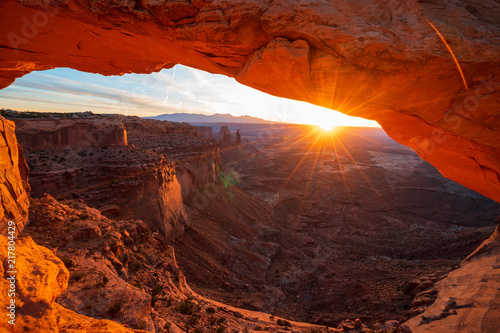 Cliff's-edge sandstone Mesa Arch framing an iconic sunrise view of the red rock canyon landscape below.