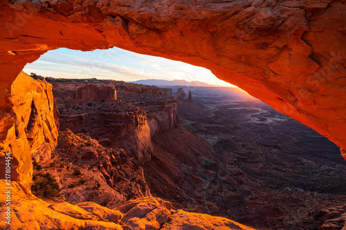 Cliff's-edge sandstone Mesa Arch framing an iconic sunrise view of the red rock canyon landscape below. © Alexander Davidovich
