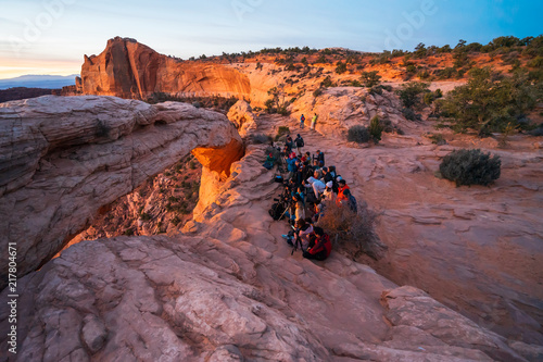Cliff's-edge sandstone Mesa Arch framing an iconic sunrise view of the red rock canyon landscape below.