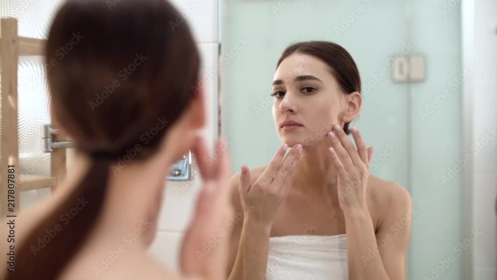 Skin Care. Woman Touching Face And Looking At Mirror At Bathroom Skin Care. Woman Touching Face And Looking At Mirror At Bathroom