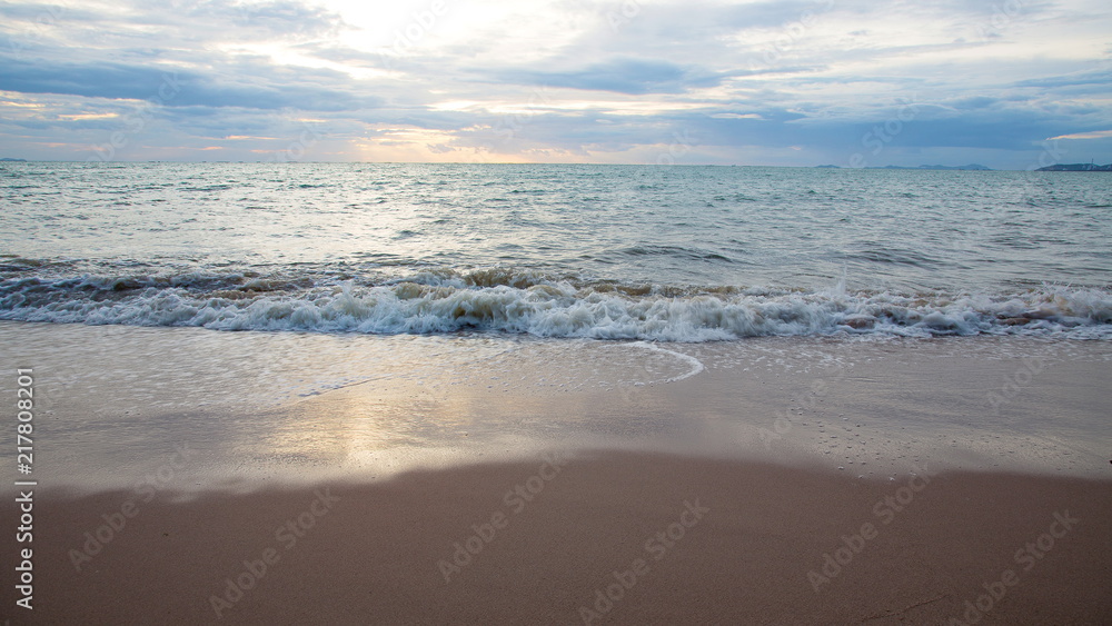 Sand beach with sea waves in the sunset.