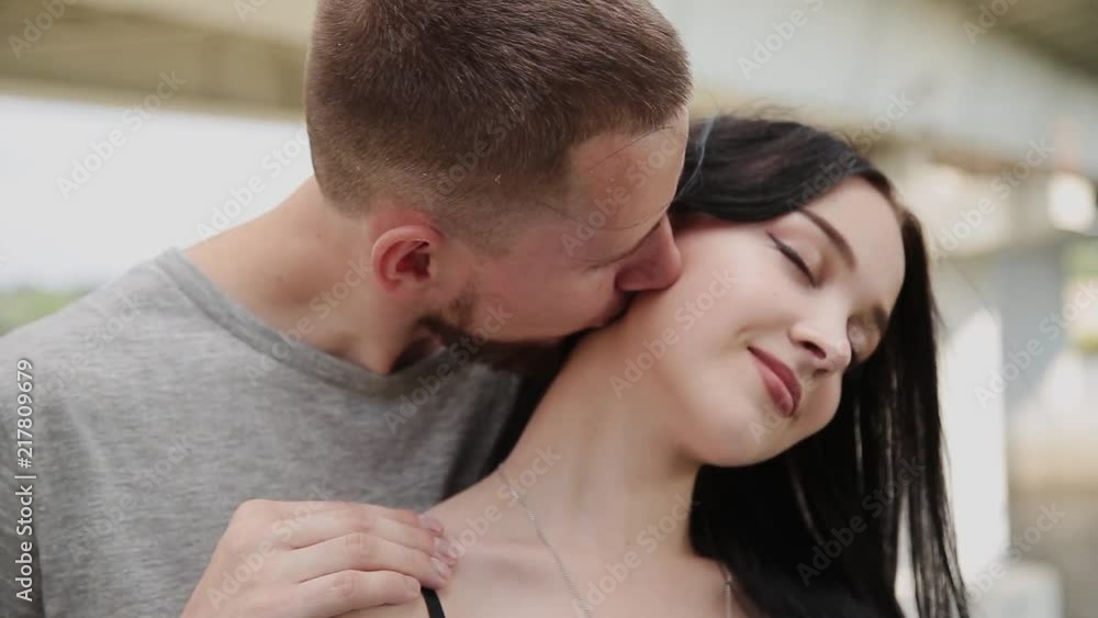 A loving couple are standing under a bridge hugging and kissing. A loving couple are standing under a bridge hugging and kissing.