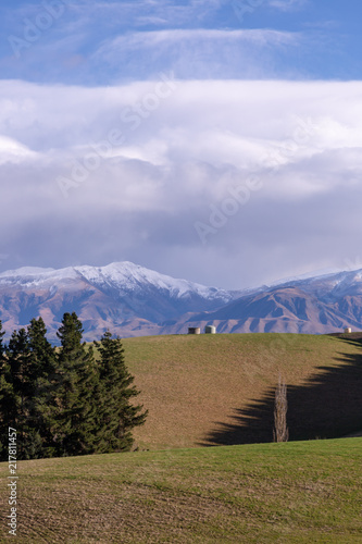 Rolling hills and farm land with snow capped mountains in the background