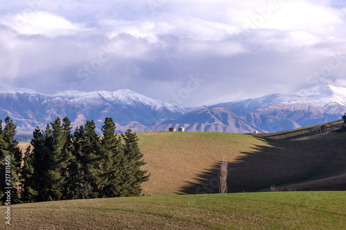 Rolling hills and farm land with snow capped mountains in the background