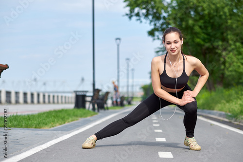 Fitness young asian woman stretching legs after run. outdoors after run
