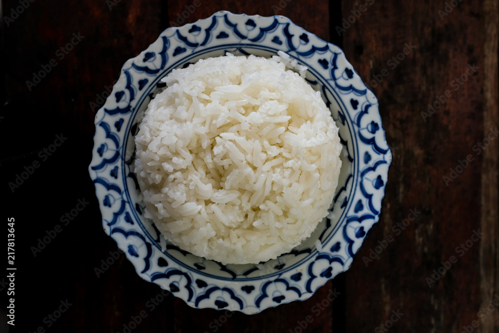 A flat lay of cooked rice in a Thai Chinese bowl on a wooden table A flat lay of cooked rice in a Thai Chinese bowl on a wooden table