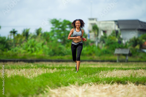 healthy lifestyle portrait of young happy and fit Asian Chinese runner woman in running workout outdoors at green field background in body fitness concept