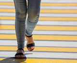 Legs of a girl crossing the road through a zebra