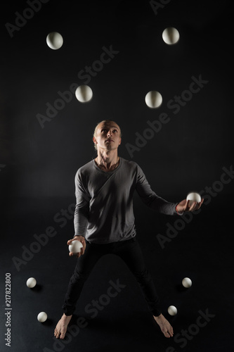 Blonde hair juggler with white balls on black background © Hladchenko Viktor