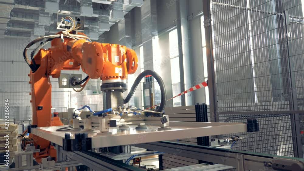 Robotic Arm works at modern factory facility. Robotic Arm works at modern factory facility.