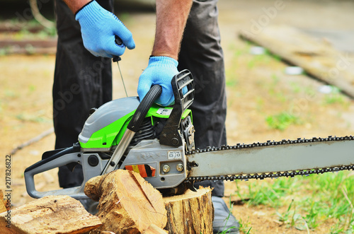 A man in gloves starts a chainsaw