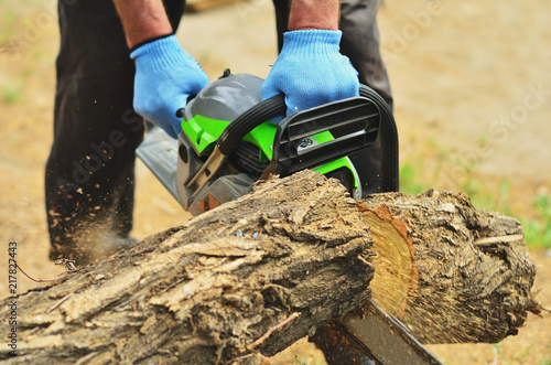 A man saws a log chainsaw, a piece of deck