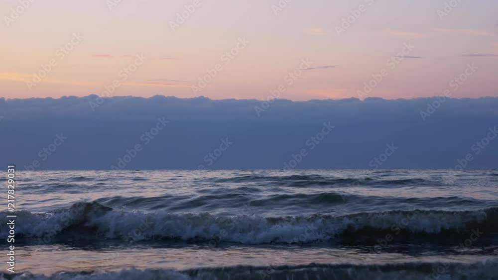 Beautiful magic sunset on the sea coast. The camera is low relative to the waves, almost on the water. The waves are big and go straight to us. Beautiful magic sunset on the sea coast. The camera is low relative to the waves, almost on the water. The waves are big and go straight to us.