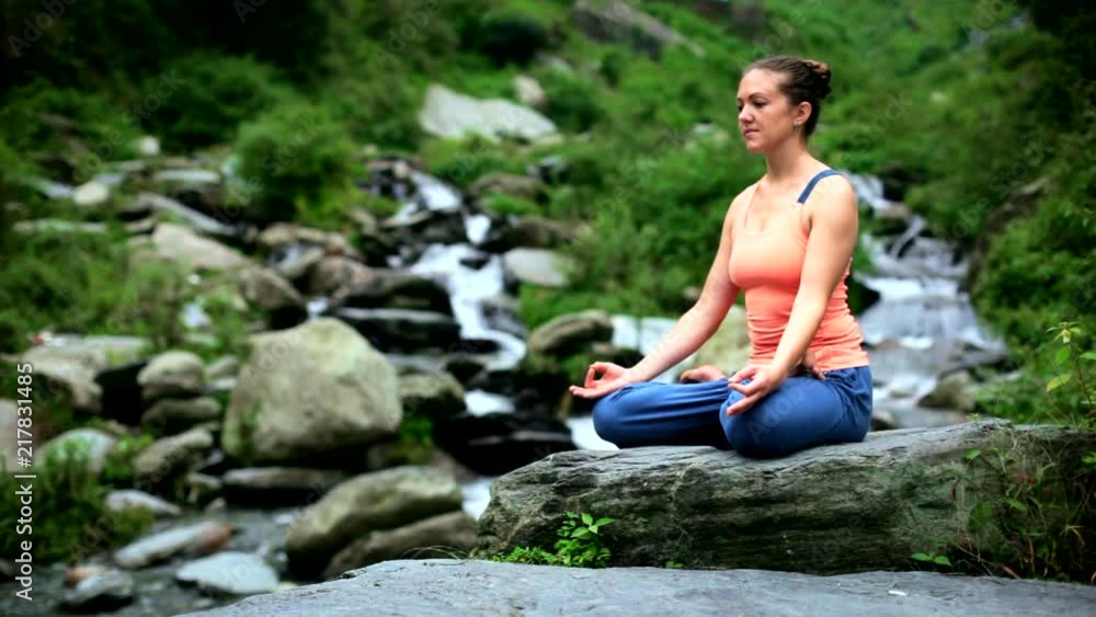 Woman meditating at tropical waterfall Woman meditating at tropical waterfall