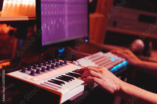 musician hands playing midi keyboard synthesizer for recording music on computer in digital sound studio