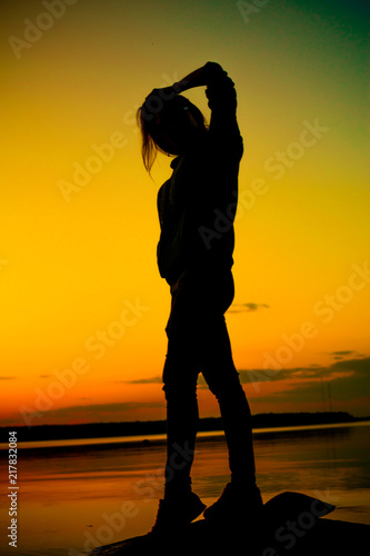 Fototapeta Naklejka Na Ścianę i Meble -  Silhouette of young woman at sunset