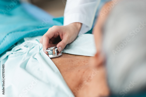 Close up doctor hand examining old asian patient by using stethoscope at man chest