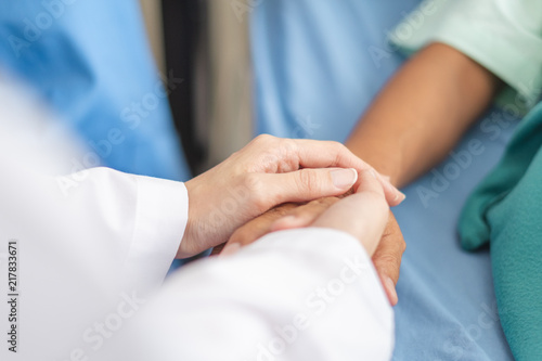Asian doctor woman encourage disabled old patient by holding hand