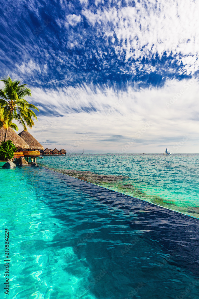 Palm tree hanging over infinity pool and ocean, Tahiti, French Polynesia