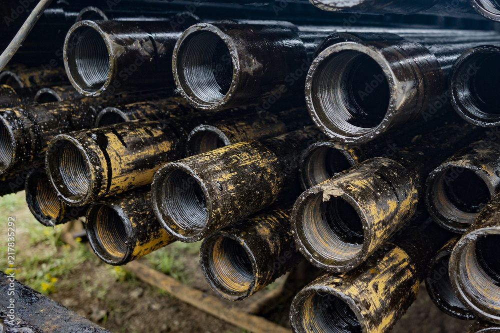 Oil Drill pipe. Rusty drill pipes were drilled in the well section. Downhole drilling rig. Laying the pipe on the deck. View of the shell of drill pipes laid in courtyard of the oil and gas warehouse. Oil Drill pipe. Rusty drill pipes were drilled in the well section. Downhole drilling rig. Laying the pipe on the deck. View of the shell of drill pipes laid in courtyard of the oil and gas warehouse.