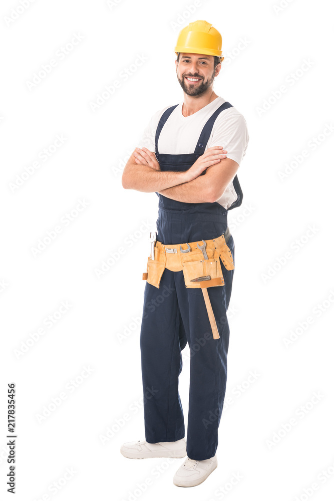 full length view of handsome happy workman in hard hat and tool belt standing with crossed arms and smiling at camera isolated on white full length view of handsome happy workman in hard hat and tool belt standing with crossed arms and smiling at camera isolated on white