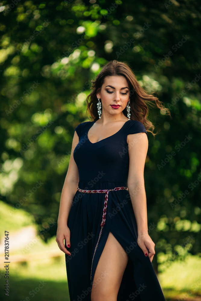 A beautiful girl in a blue dress is walking in the park. Sunny A beautiful girl in a blue dress is walking in the park. Sunny