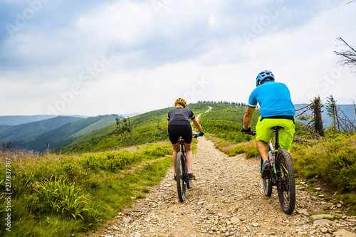 Cycling, mountain biker couple on cycle trail in autumn Mountains. Man and woman cycling MTB flow trail.