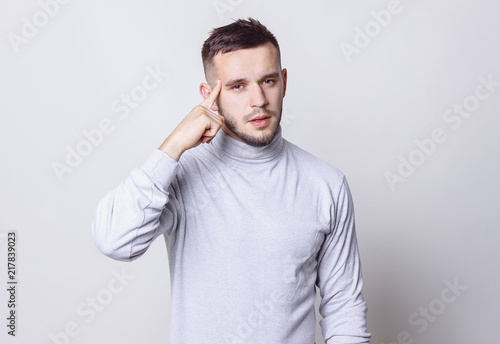 Handsome man thinking with finger on head grey background copy space