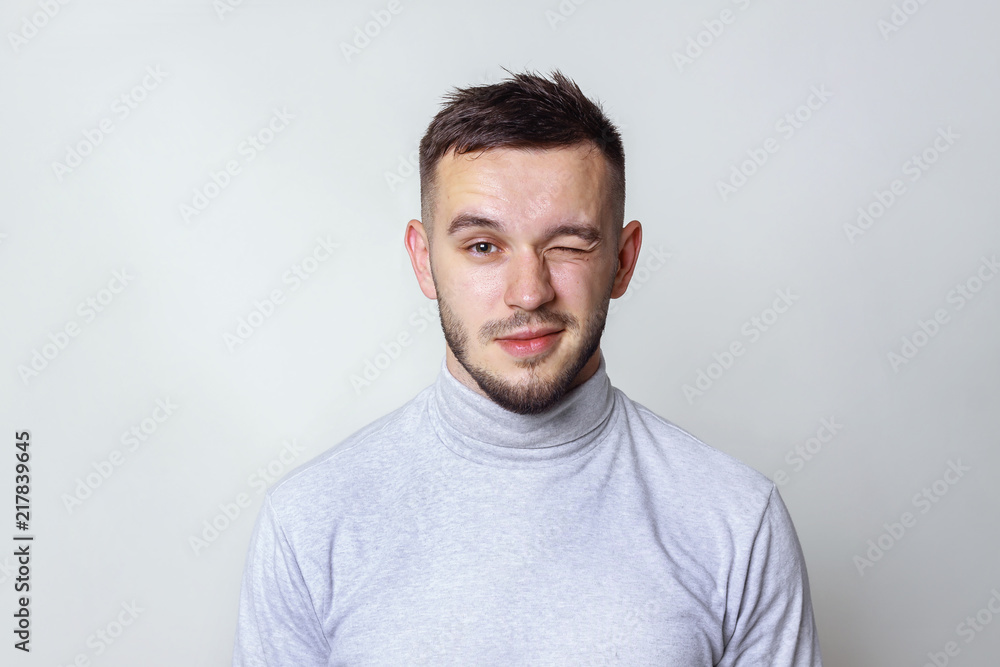Handsome man looking at camera and winking. isolated on gray, copy space Handsome man looking at camera and winking. isolated on gray, copy space