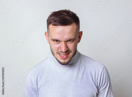 Insane or mad evil look concept a portrait mean looking man staring directly at viewer on grey background copy space