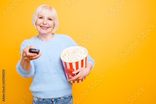 Happy grandmother holds a bucket of sweet white popcorn and joyf