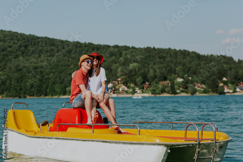Shot of happy couple sitting on pedal boat. Young man and woman in love enjoying boating in the lake. © Newman Studio