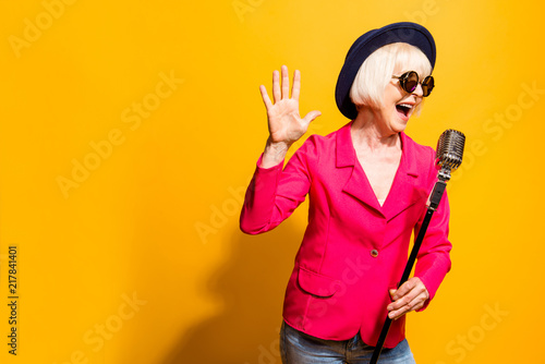 Portrait of charming modern grandmother holds up the microphone 