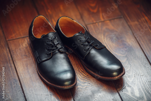 Black leather male shoes on wooden background