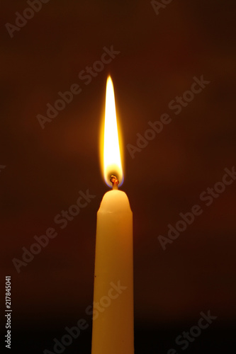 big paraffin flaming candle with big fire against the dark background.